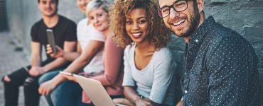 Hero photo for post announcing free SmartRecruiters demo for Google Hire Customers. Photo is of four young people of varying ethnic backgrounds sitting together and working together.