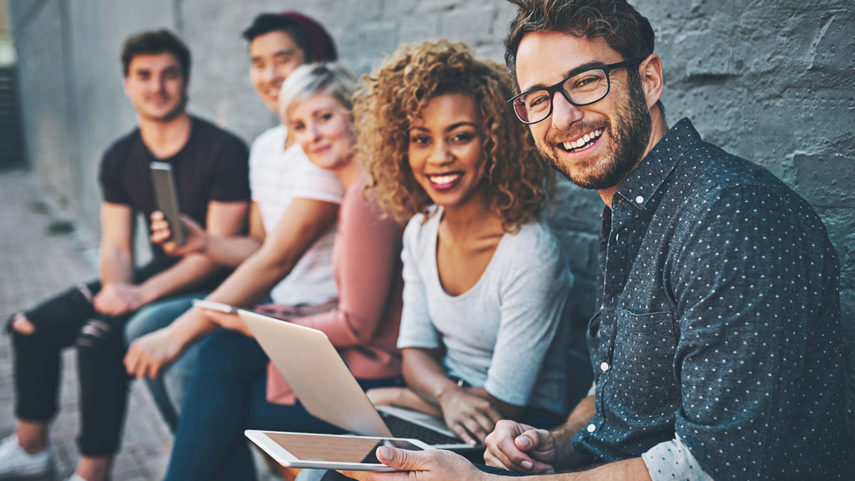 Hero photo for post announcing free SmartRecruiters demo for Google Hire Customers. Photo is of four young people of varying ethnic backgrounds sitting together and working together.